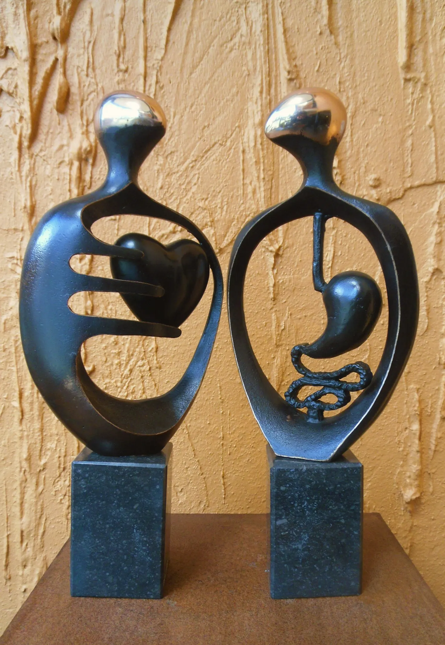 Twee bronzen figuren met een hart en een maag in hun silhouet.